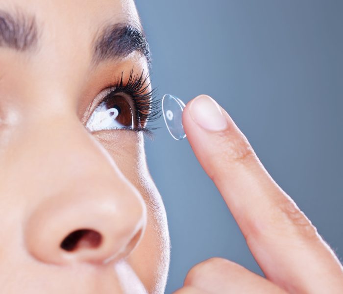 Face, woman and eye care with contact lens, iris and optometry with closeup in blue background. Female person, ophthalmology and zoom for wellness, and cosmetic in studio backdrop for sight or vision.